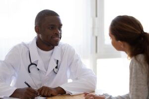 Smiling african american doctor talks to woman in clinic